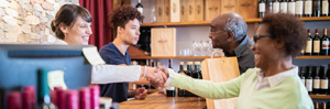 Retail wine shop with customer shaking hand with cashier.