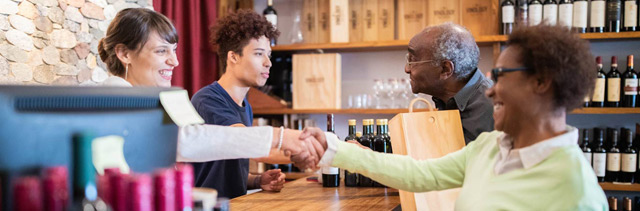 Retail wine shop with customer shaking hand with cashier.