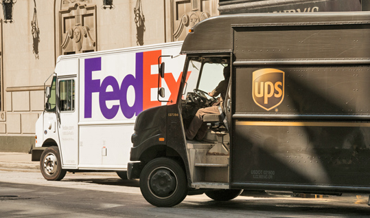 Photo of FedEx and UPS trucks in front of a building.