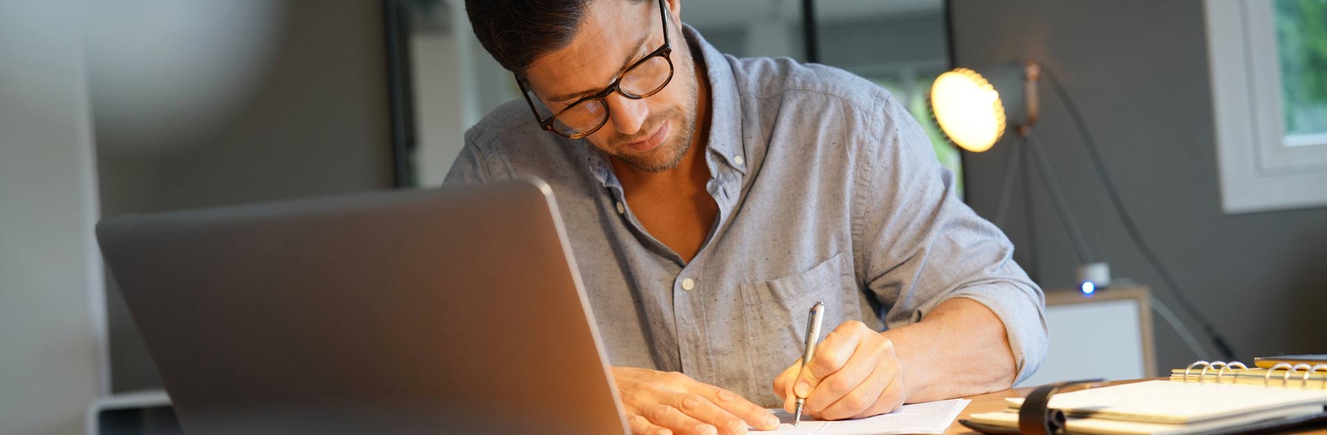 Man looking down and working on his accounting at desk.
